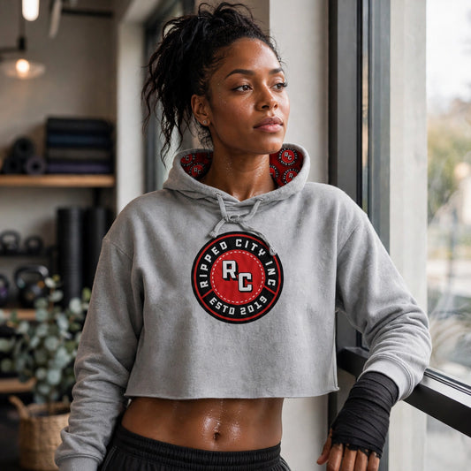 Athletic model in a gray Ripped City cropped fleece hoodie with RC badge, gym scene