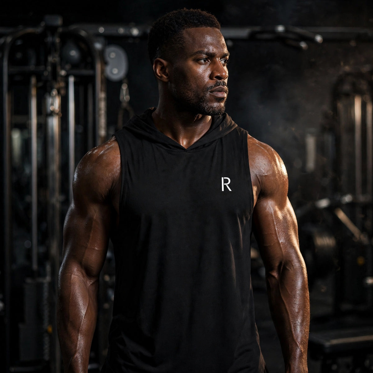 Athletic model in a black Ripped City hoodie tank top with small white R logo, gym scene