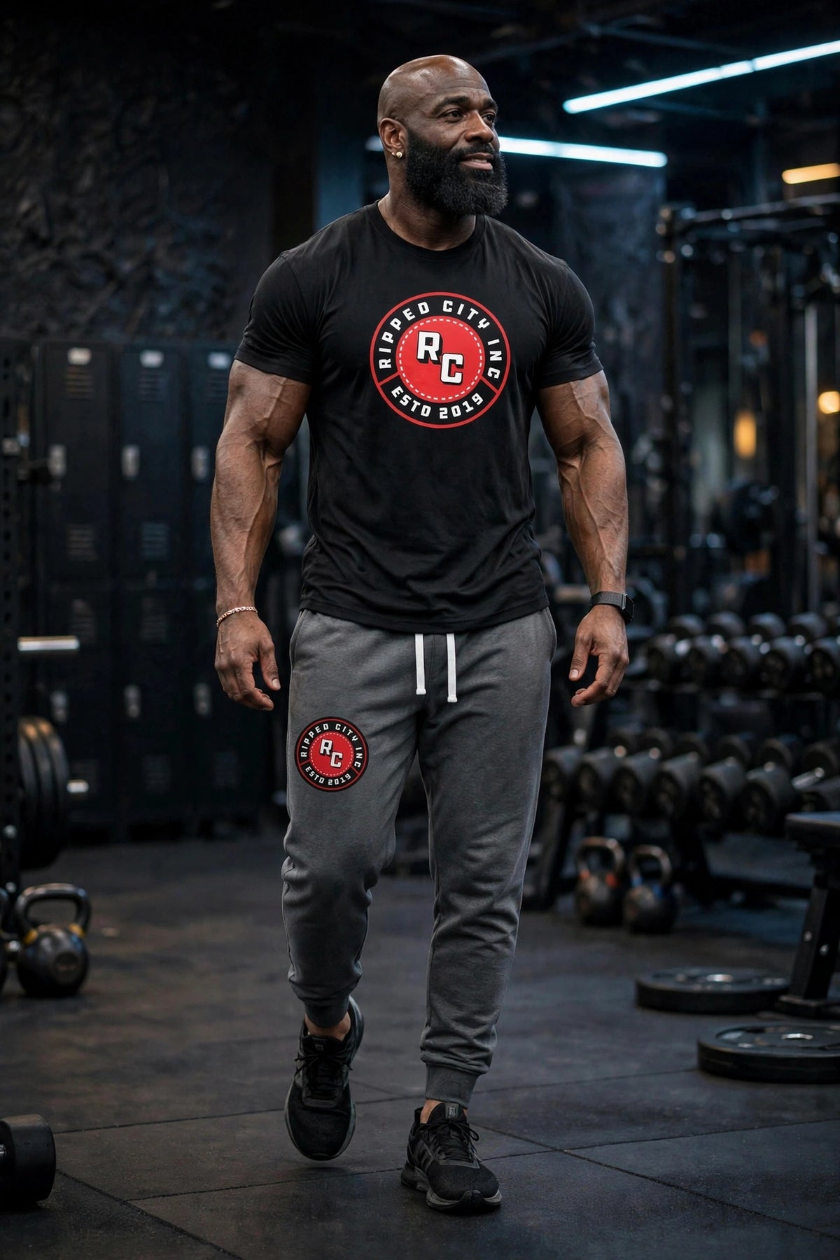 Athletic model in black Ripped City joggers and black tee with RC badge, gym setting