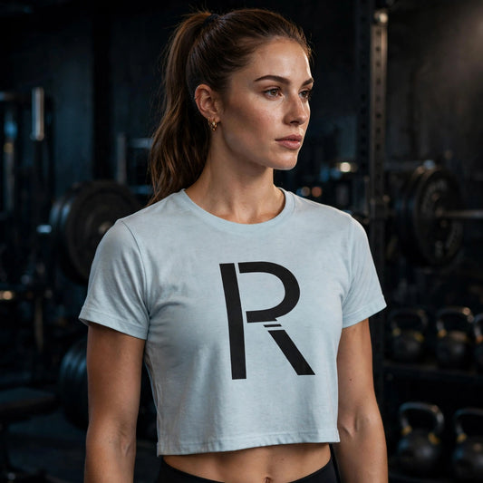 Athletic model in a light blue Ripped City crop tee with large black R, gym setting