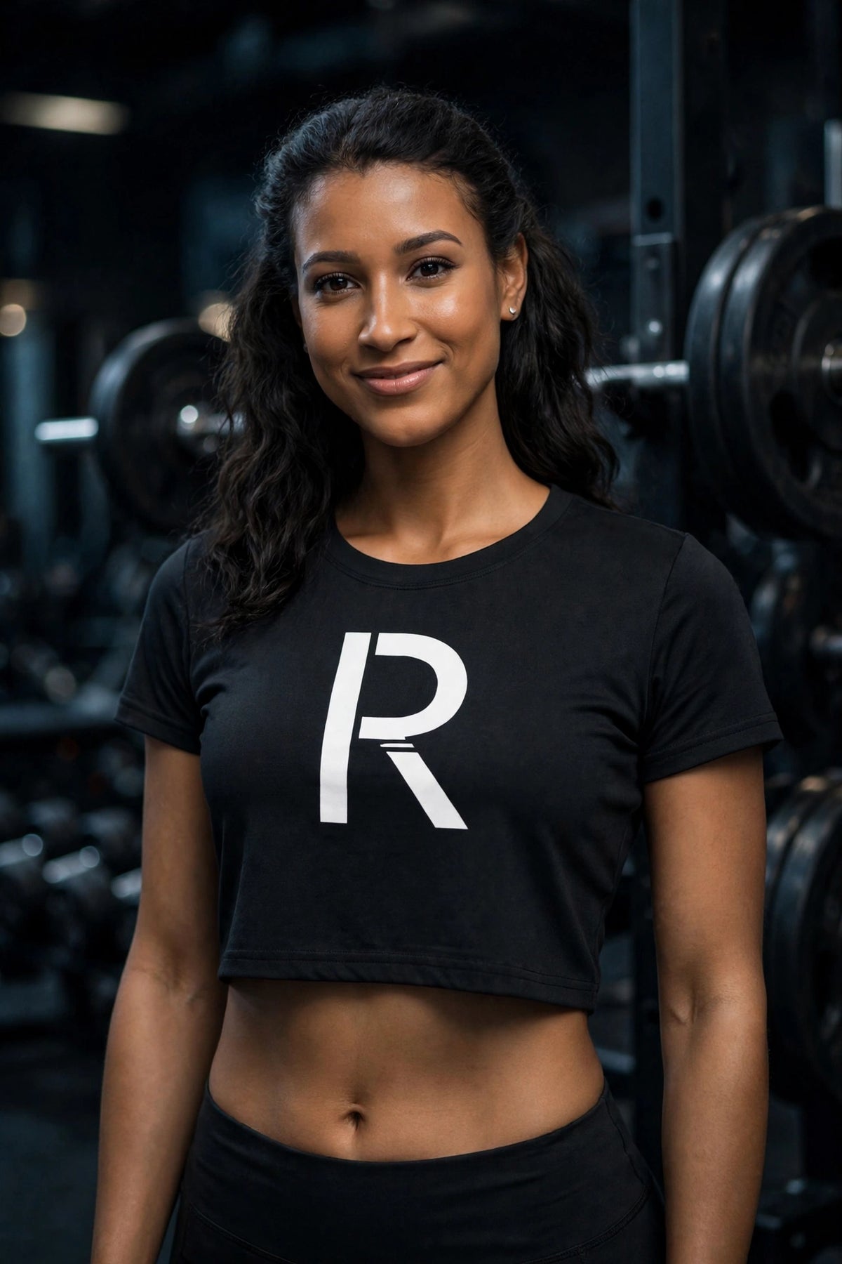 Athletic model in a black Ripped City crop tee with white R centered, gym scene