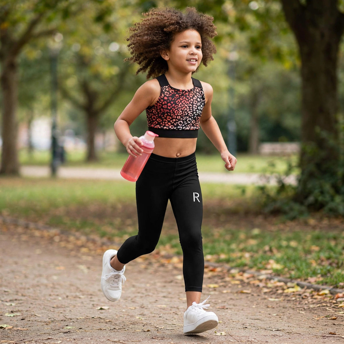 Young athlete in black Ripped City girls' leggings with R logo, gym setting