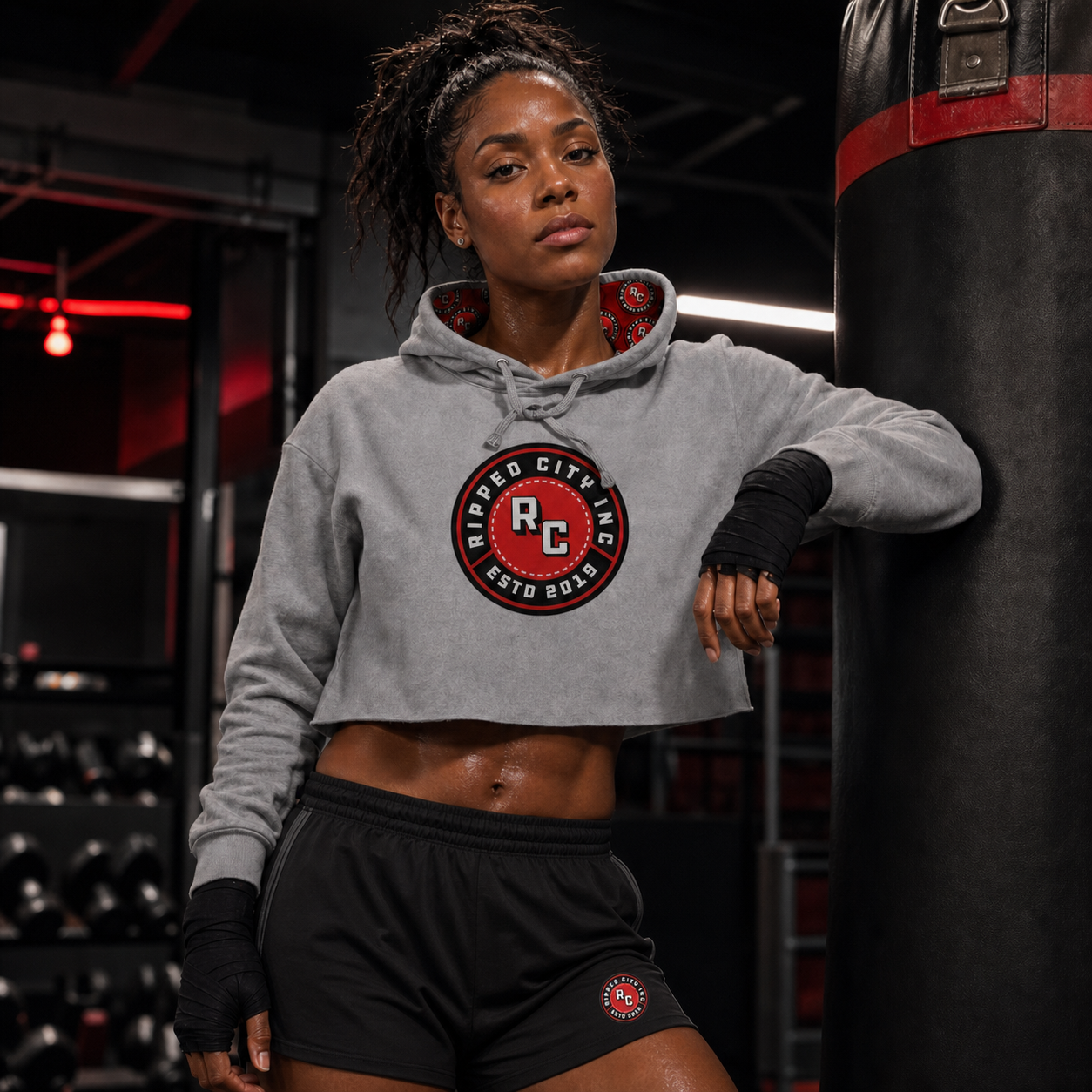 Strong woman wearing a coordinated Ripped City crop hoodie and training shorts outfit - Ripped City Inc premium gym apparel